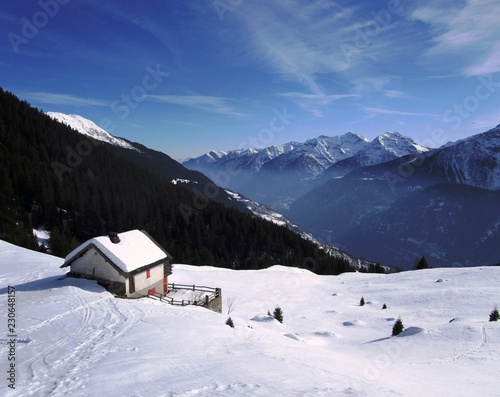 Casetta sulla neve con montagne e cielo blu