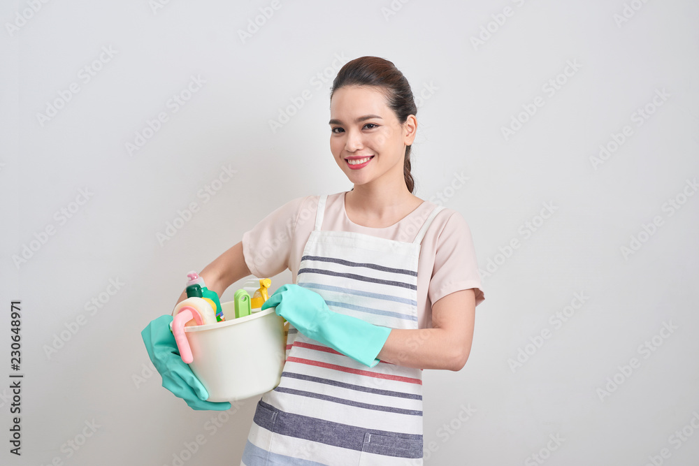 Cleaning services concept. Young cheerful woman holding bucket with detergents and rags at white isolated background. Household and home cleaning Cleaning services concept. Young cheerful woman holding bucket with detergents and rags at white isolated background. Household and home cleaning