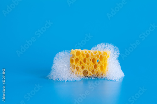 Bild auf Leinwand Cleaning yellow sponge soapy bubbles foam on blue background