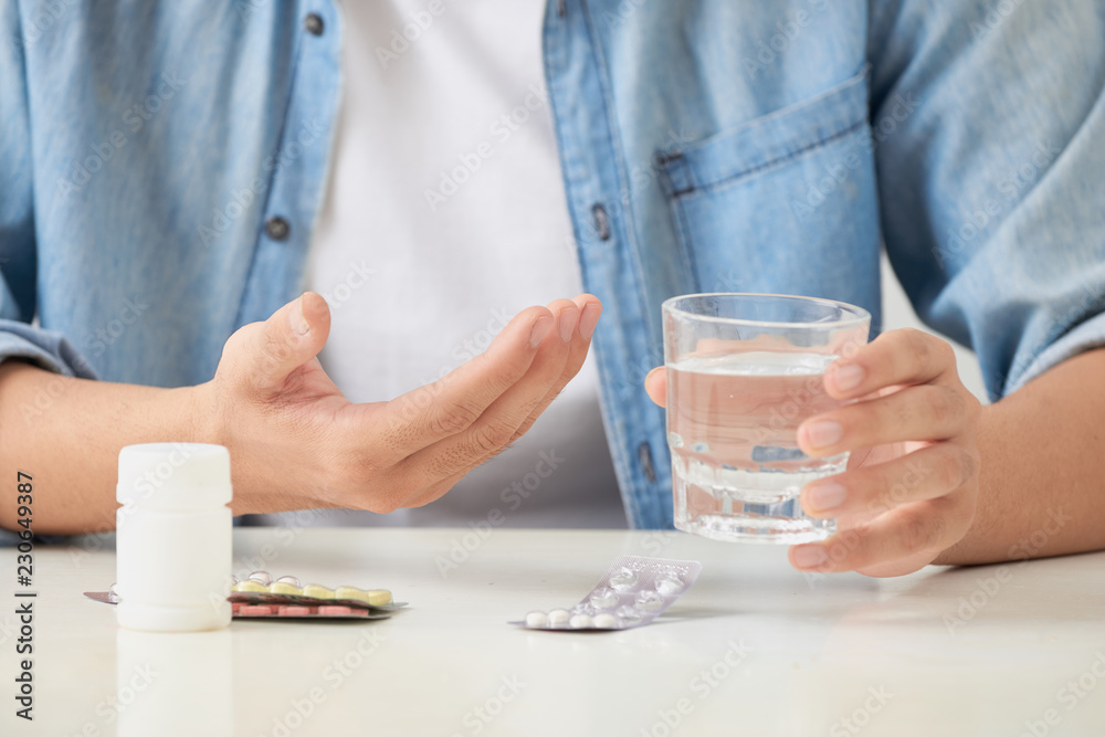 Man taking his pills on couch in the living room Man taking his pills on couch in the living room