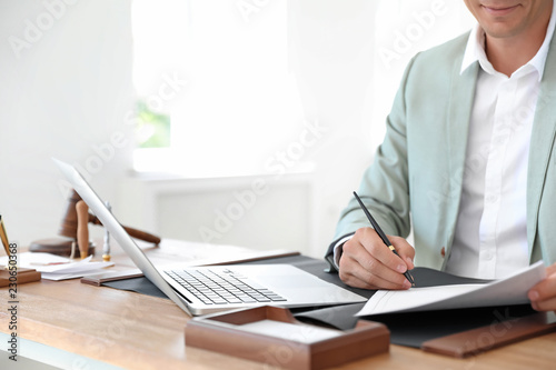 Male notary signing document at table in office, closeup