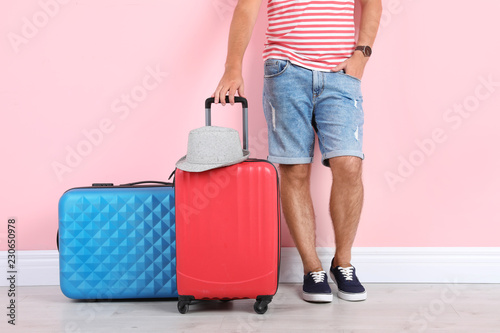 Man with suitcases near color wall. Vacation travel
