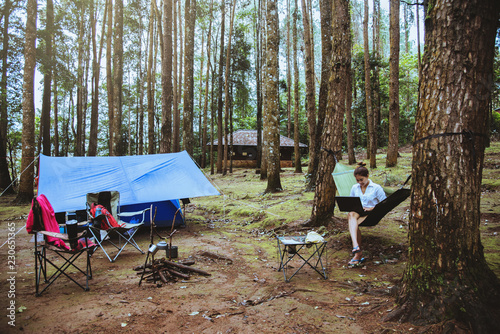 Asian women travel natural relax . Sitting working using a notebook. in the hammock. campsite on the national park Doi inthanon at Chiangmai. in Thailand