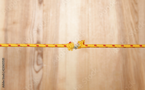 Frayed rope at breaking point on wooden background