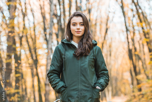 Beautiful young woman in jacket looking at camera in autumnal forest