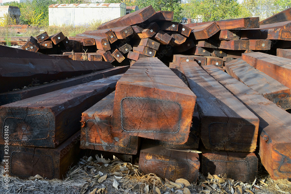 A pile of brown wooden railway sleepers outdoor on a sunny autumn day