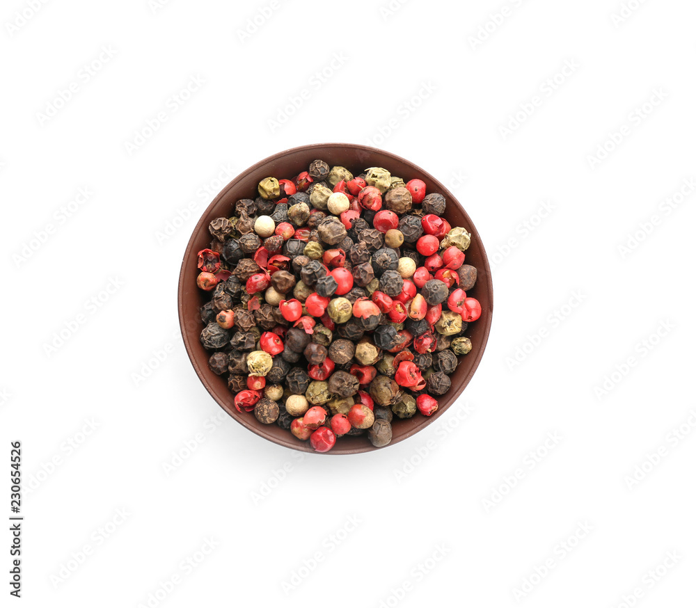 Bowl with different pepper grains on white background, top view