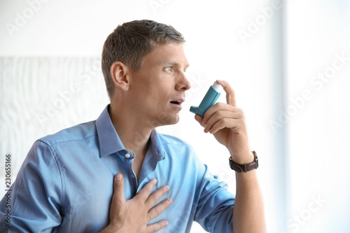 Schilderij op canvas Young man using asthma inhaler at home