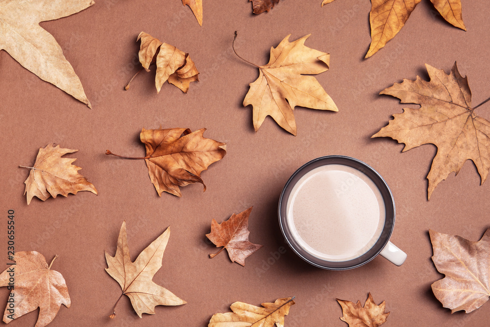 Flat lay composition with hot cozy drink and autumn leaves on color background