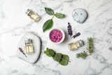 Different essential oils and ingredients on marble background, flat lay