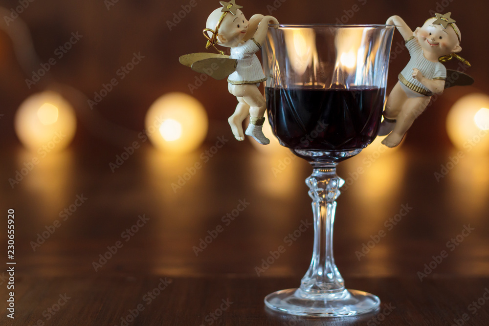 Glass of red wine with Christmas decoration with lights in the background