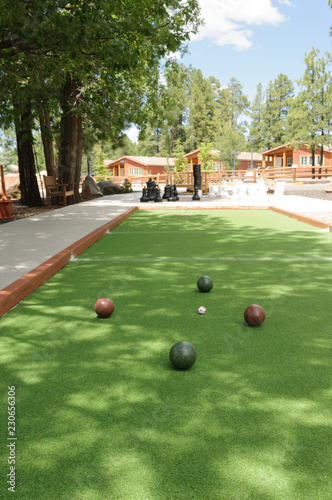 Four Bocce Balls and a pallino ball on a green bocce court.