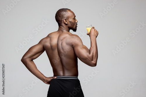 Fit young man with beautiful torso, isolated on white background. The naked torso of African American man posing at studio. The muscular body, fitness, sports, healthy lifestyle and bodybuilder
