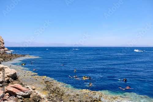 Unrecognized tourists snorkeling in Blue Hole lagoon on Red Sea, Sinai coast of Egypt.