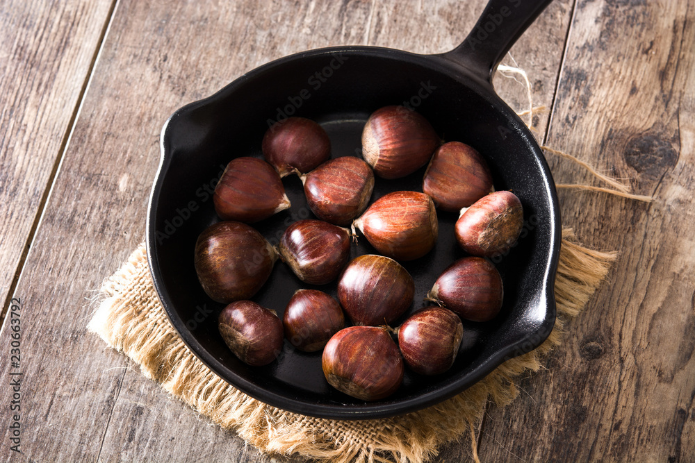 Obraz premium Chestnuts in iron pan on wooden table