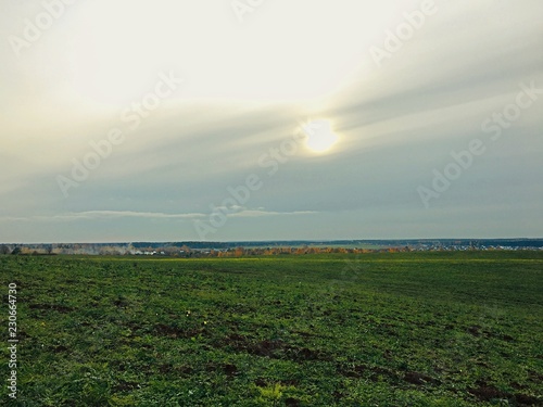 The sun behind the clouds over the village in autumn