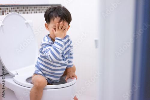 Little boy poo and pee in white toilet.