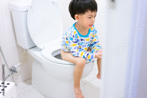 Little boy poo and pee in white toilet.