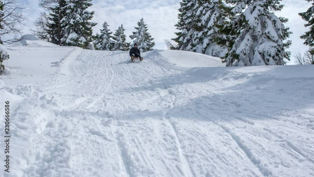 There is a lot of snow for fun winter activities. It's a nice day and this guy decided to go sledding down the hill. He is enjoying it. There is a lot of snow for fun winter activities. It's a nice day and this guy decided to go sledding down the hill. He is enjoying it.