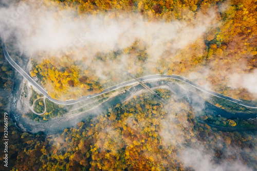 Aerial view of a highway trough the mountains with fog and railroad