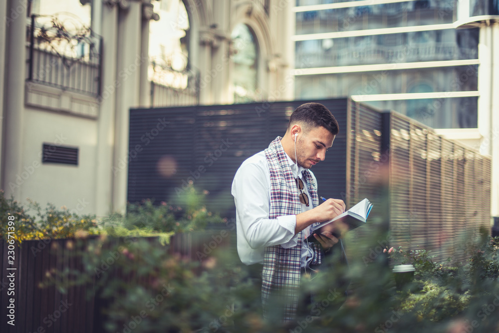 Good looking businessman is writing at his notebook Good looking businessman is writing at his notebook