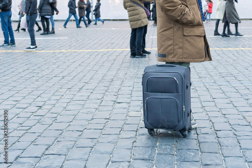 Traveler stands in the square with a suitcase