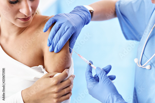 Adult woman having injection during visit at female doctor's office