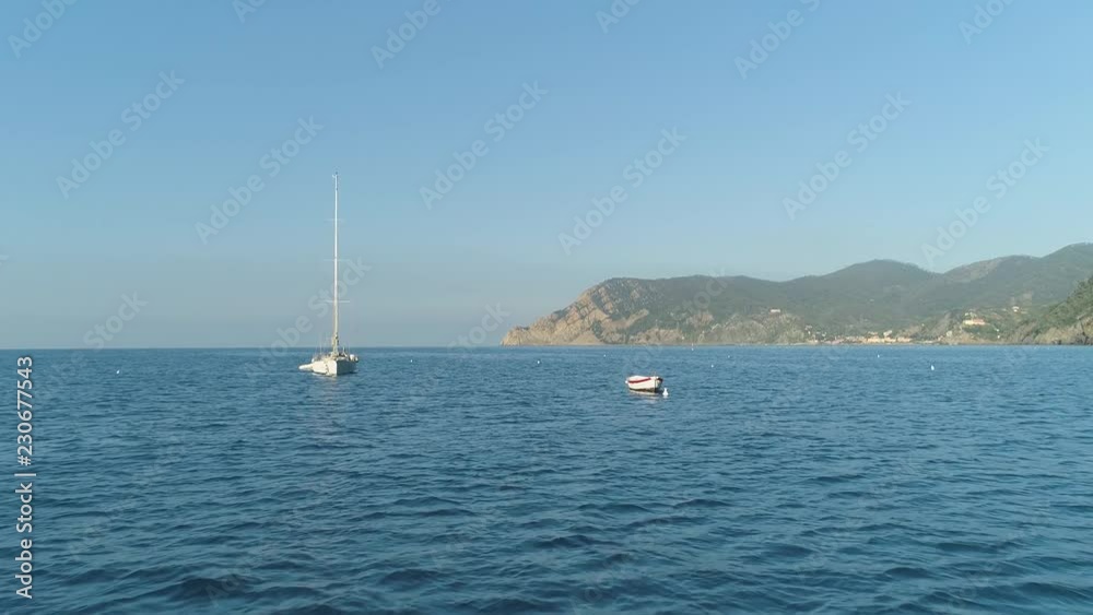 Aerial: Slow Motion Yacht parked in open sea Close to mountain cliff shore Aerial: Slow Motion Yacht parked in open sea Close to mountain cliff shore