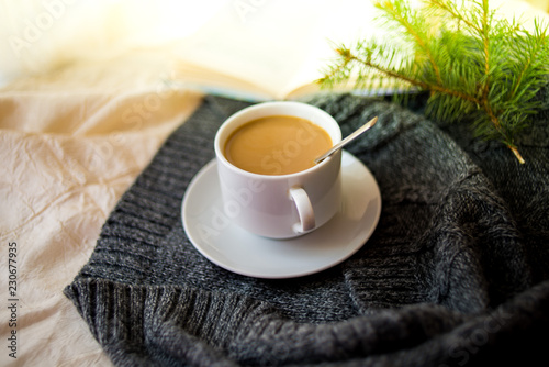 cup of tea with milk on a textile background with a knitted sweater and needles.