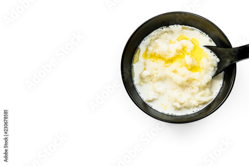 tasty rice porridge with butter in a black bowl with a blackl spoon, healthy food, diet photo