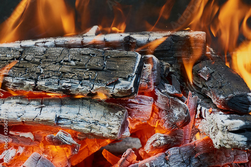 A beautiful red flame on wooden firewood. Dark gray and black coals. Preparation of coals from firewood for cooking barbecue