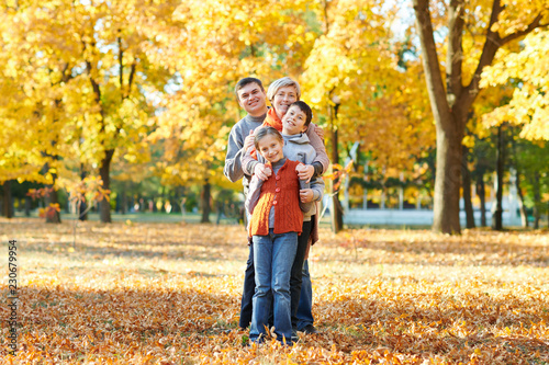 Happy family walks in autumn city park. Children and parents posing, smiling, playing and having fun. Bright yellow trees.