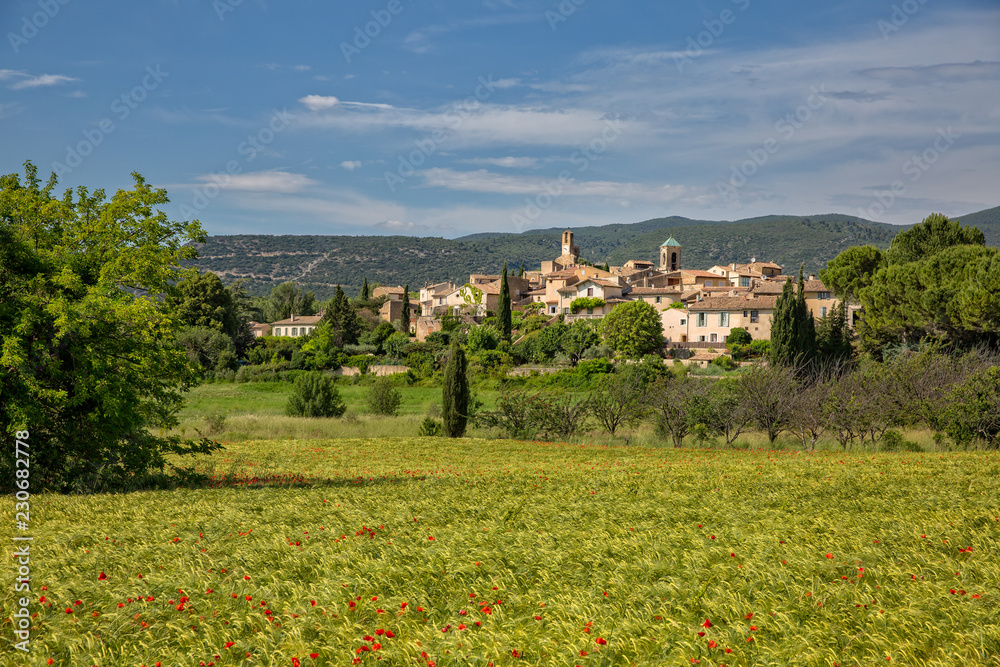 Blick auf das idyllische Dorf Lourmarin mit Weizenfeld und Mohnblumen, Provence, Luberon, Vaucluse, Frankreich 
