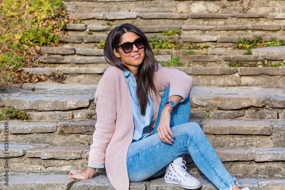 Beautiful Smiling Young Woman with Black Sunglasses Sitting on a Stairs Beautiful Smiling Young Woman with Black Sunglasses Sitting on a Stairs
