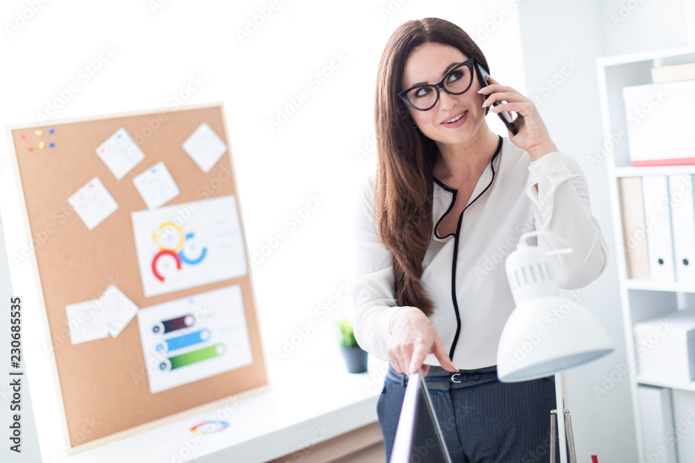 A young girl standing near the table and talking on the phone. A young girl standing near the table and talking on the phone.