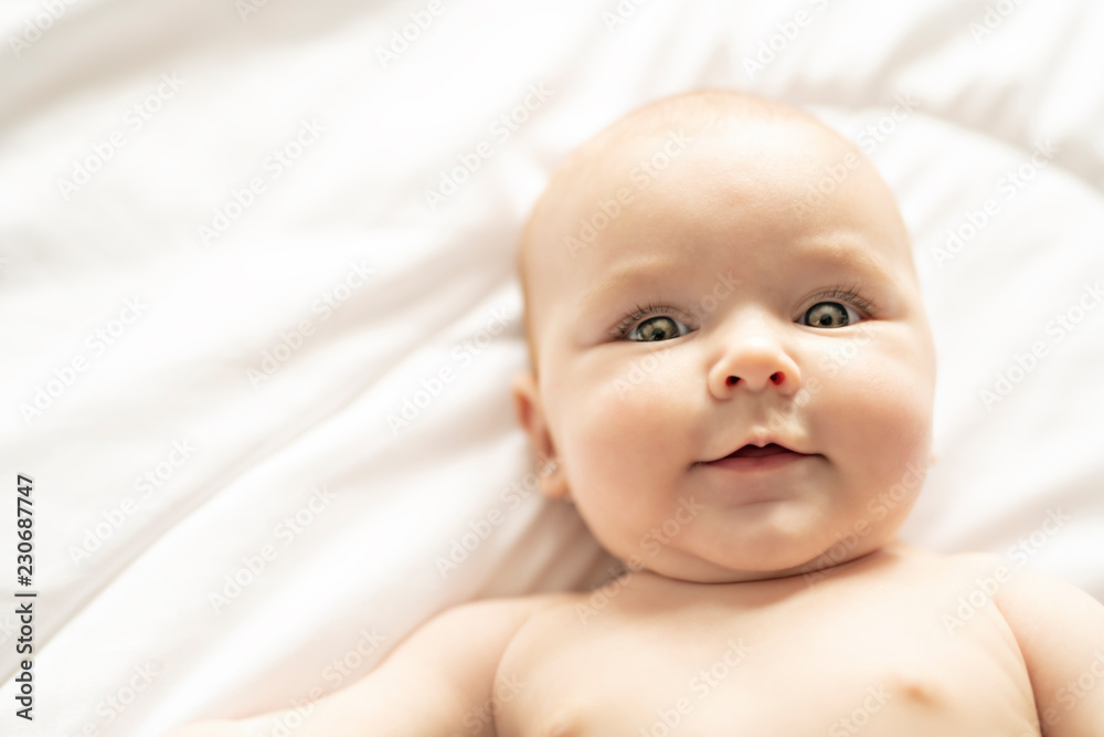 A Cute baby girl on a white bed at home A Cute baby girl on a white bed at home