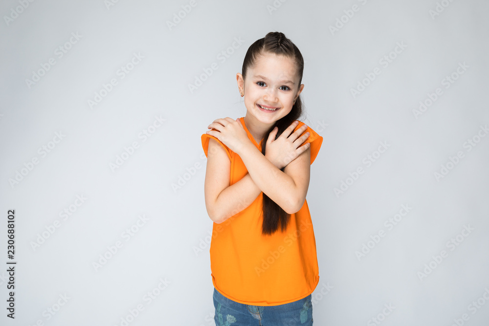 Girl on a gray background folded his hands at his chest. Girl on a gray background folded his hands at his chest.