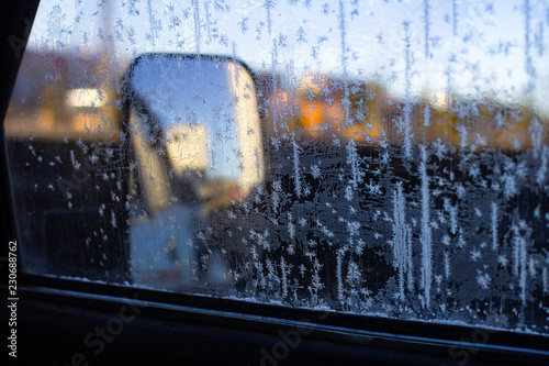 Inside frozen car, glass view, window covered with ice, early morning winter season