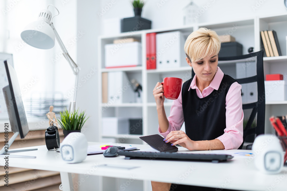Girl sitting in the office at the table and drinking coffee. Girl sitting in the office at the table and drinking coffee.