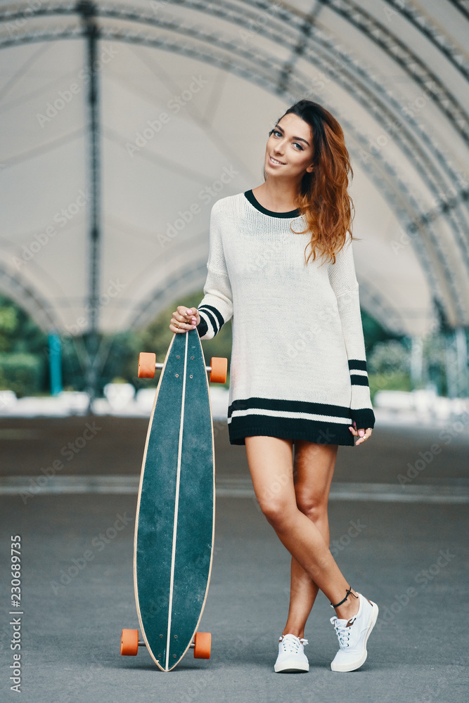 Pretty woman posing wit longboard in a street