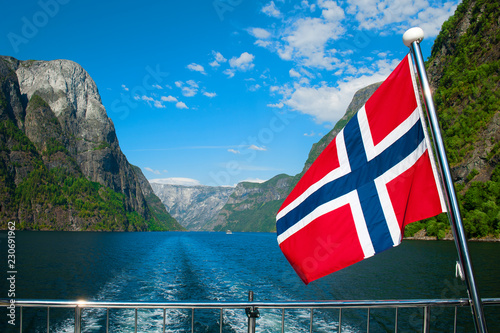 The Breathtaking Norwegian Aurlandsfjord and Naeroyfjord - UNESCO protected fjord - cruise (Flam- Gudvangen) on Norway in a Nutshell Tour. One of the narrowest fjords in Europe Naeroyfjord and a flag.