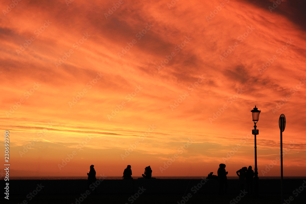 Colorful Sunset Sky and Vibrant Bright Orange Cloudscape with Silhouettes of People on City Street. Scenic Sky Background at Sunset or Sunrise, Dusk and Dawn Beautiful Skyline View Over the City