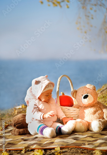 Autumn picnic by the blue sea sits a girl with a bear photo