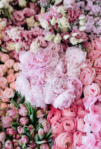 Fototapeta Naklejka Na Ścianę i Meble -  Beautiful blossoming flower bed of freshly delivered flowers at the florist shop: peonies, roses, ranunculus, tulips, carnations,eustoma lisianthks, hydrangea in tender pink colours, top view