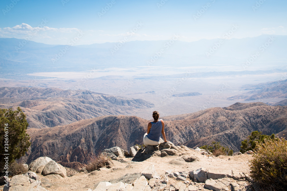 A girl viewing over Joshua Tree National Park with its typical trees and rock formations near Palm Springs in the California desert in the USA