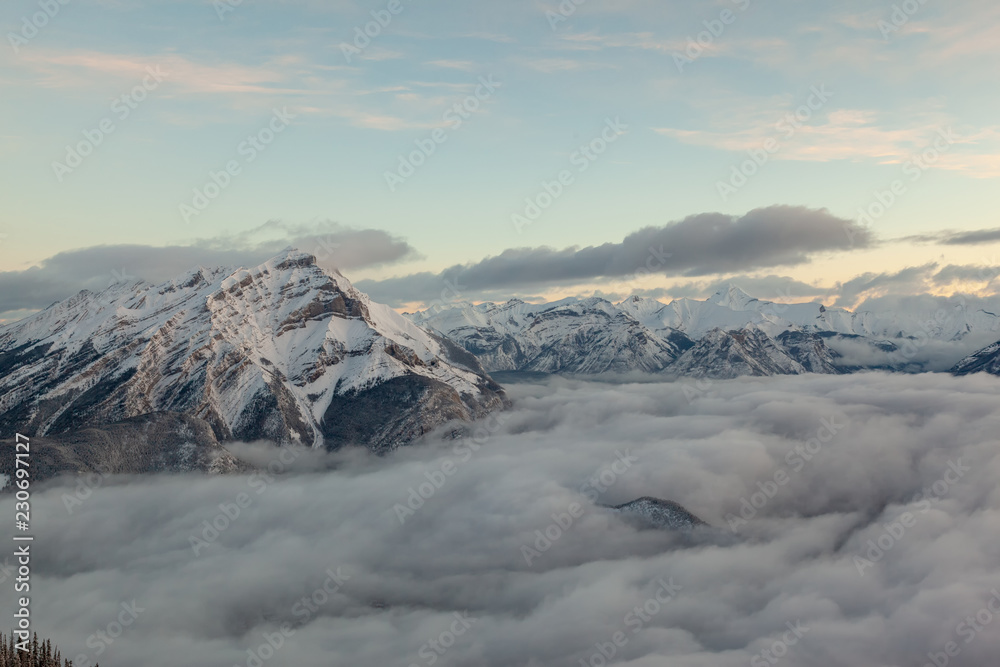 Obraz premium Winter birdview of snow capped Cascade Mountain with low cloud from the summit of Sulphur Mountain in Banff National Park in Alberta