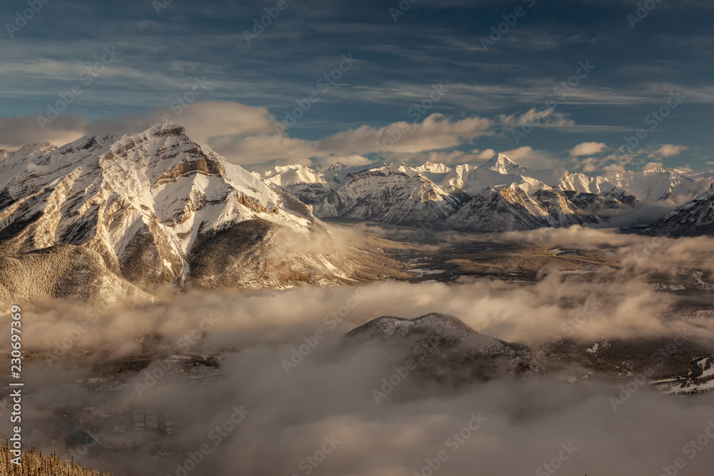 Obraz premium Winter birdview of snow capped Cascade Mountain with low cloud from the summit of Sulphur Mountain in Banff National Park in Alberta