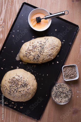 Foto The dough sprinkled with seeds in the form of baking bread