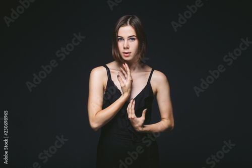 Portrait of a beautiful young Caucasian Caucasian woman 20 years old model with blue eyes natural make-up of hair on shoulder dancing hands posing on black isolated background in black lingerie