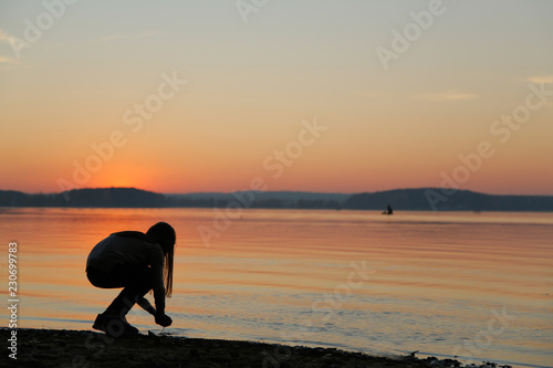 A teenager at sunset takes water in the palm of photo